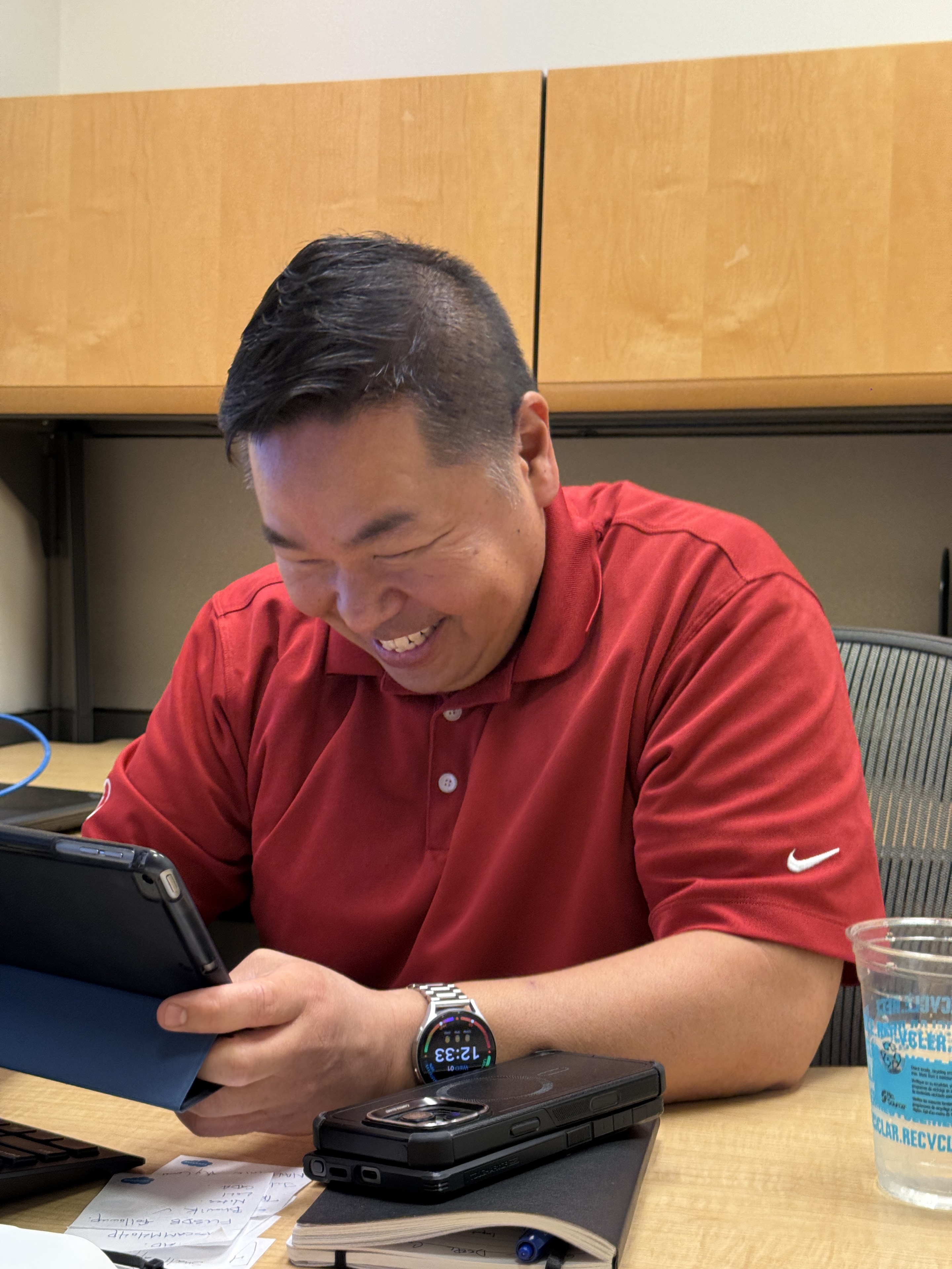Joseph Park smiling while using a tablet in a meeting room.